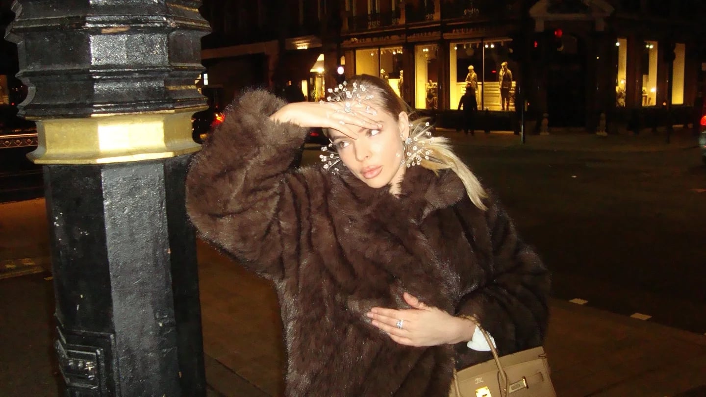 Woman raising her hand against the camera flash on a night-time street